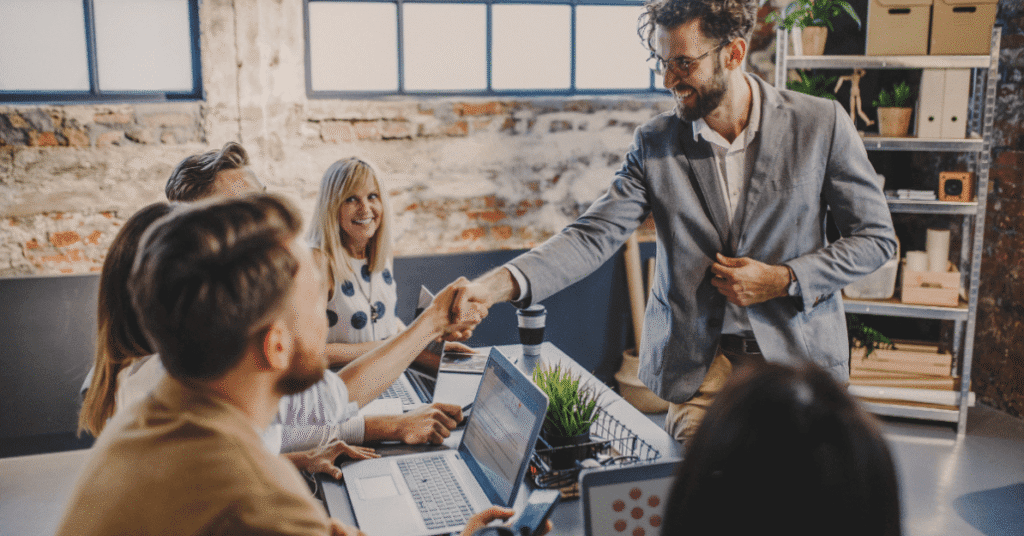 Мужчина на собеседовании пожимает руку сотруднику компании.