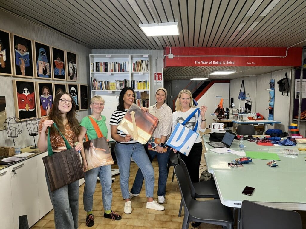 Zaměstnanci Integračního centra Praha ukazují na Erasmu v Itálii kabelky, které vyrobily. 