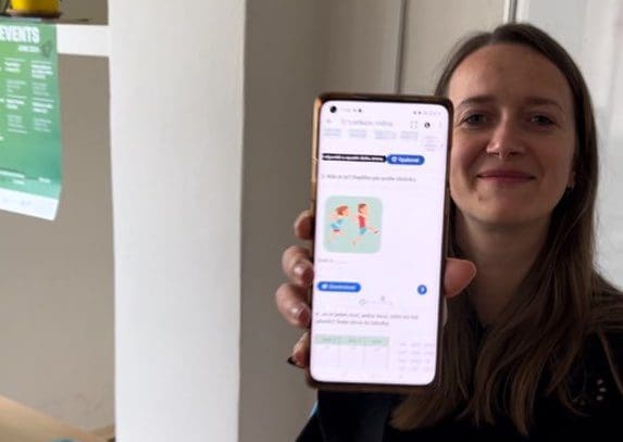 Metodička kurzů češtiny drží v ruce telefon s e-learningovým kurzem češtiny.