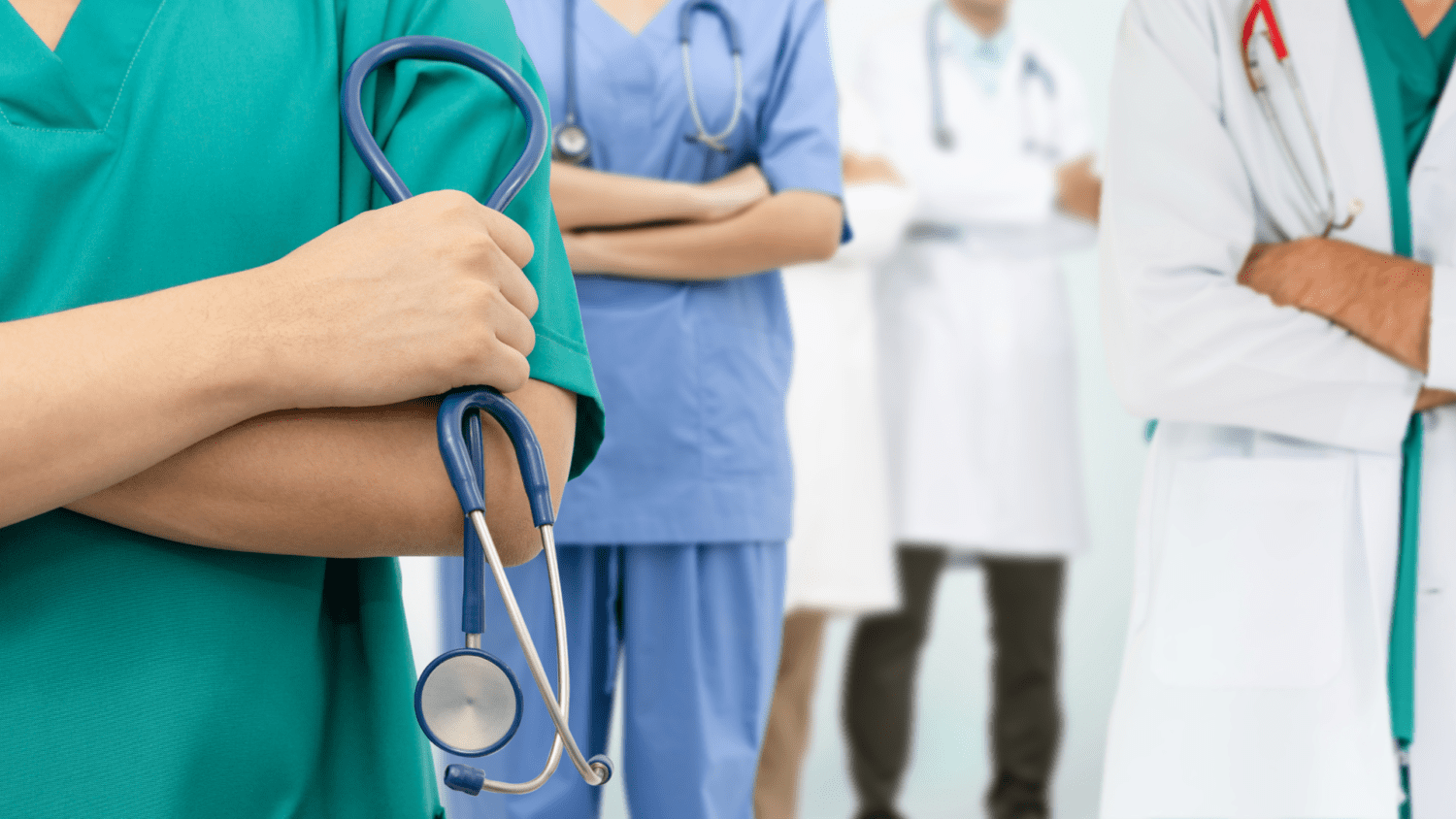 Zaměstnanci nemocnice, polikliniky nebo soukromé ordinace stojí v doktorských pláštích za sebou.