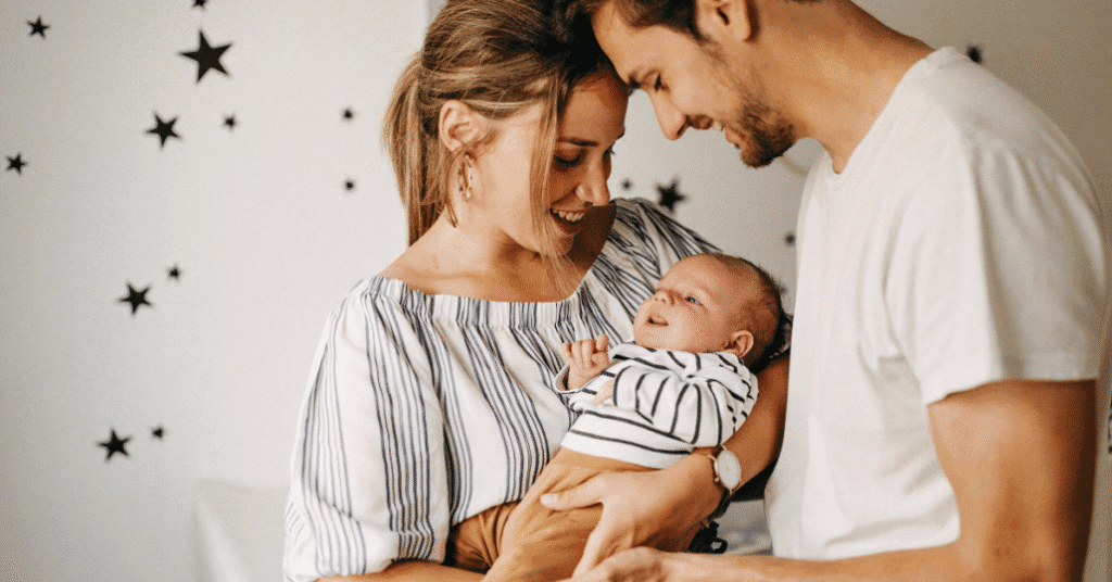 Rodiče drží v rukou malé dítě, využívají podporu v mateřství a rodičovství.